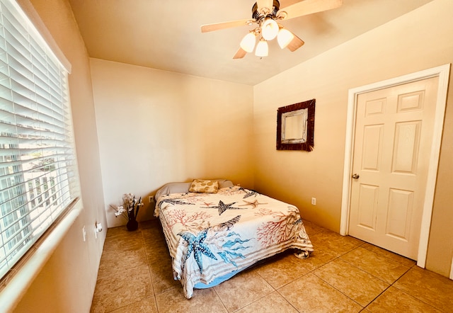 tiled bedroom with ceiling fan and multiple windows