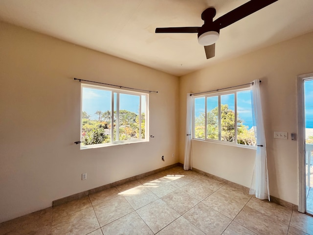 empty room featuring ceiling fan, light tile patterned floors, and a water view