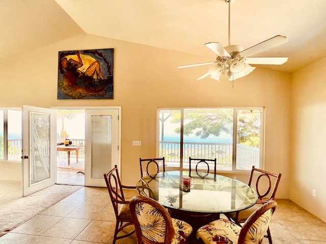 dining room featuring light tile patterned floors, lofted ceiling, a water view, and ceiling fan