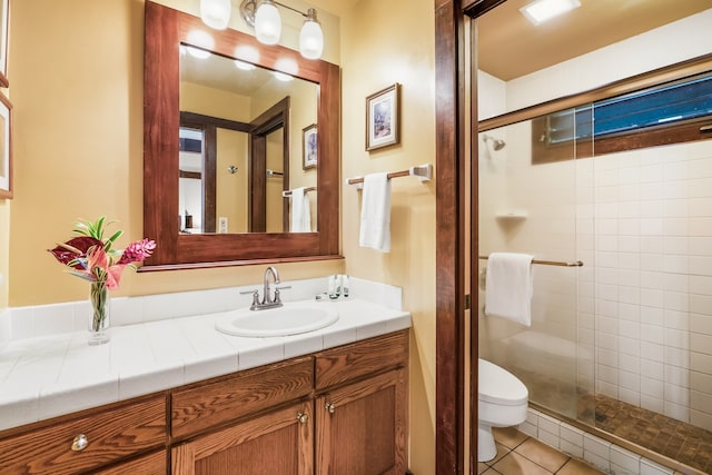 bathroom featuring tile patterned flooring, a shower with shower door, vanity, and toilet