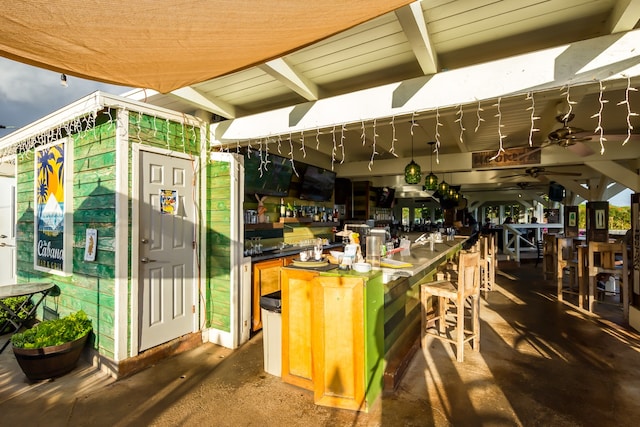 exterior space with concrete flooring, ceiling fan, and bar