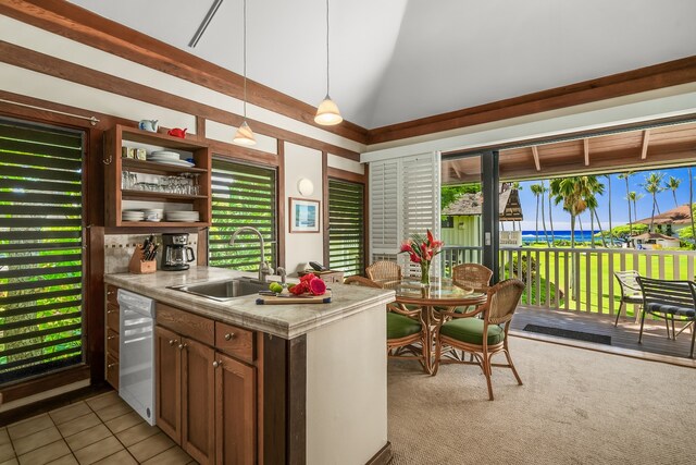 kitchen featuring white dishwasher, lofted ceiling, hanging light fixtures, light tile patterned floors, and sink