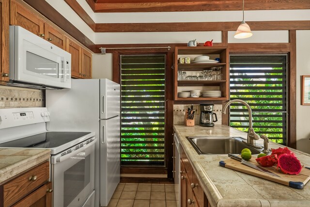 kitchen with light tile patterned floors, sink, white appliances, decorative light fixtures, and decorative backsplash