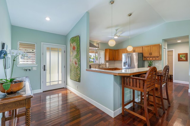 kitchen featuring vaulted ceiling, dark hardwood / wood-style floors, stainless steel fridge, ceiling fan, and kitchen peninsula