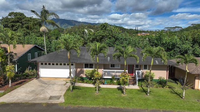 single story home featuring a mountain view, a porch, a garage, and a front yard