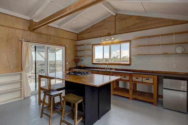 kitchen with beamed ceiling, sink, stainless steel appliances, high vaulted ceiling, and a center island