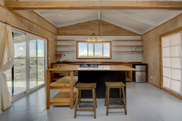 kitchen with wood-type flooring, vaulted ceiling with beams, stainless steel fridge, and butcher block countertops