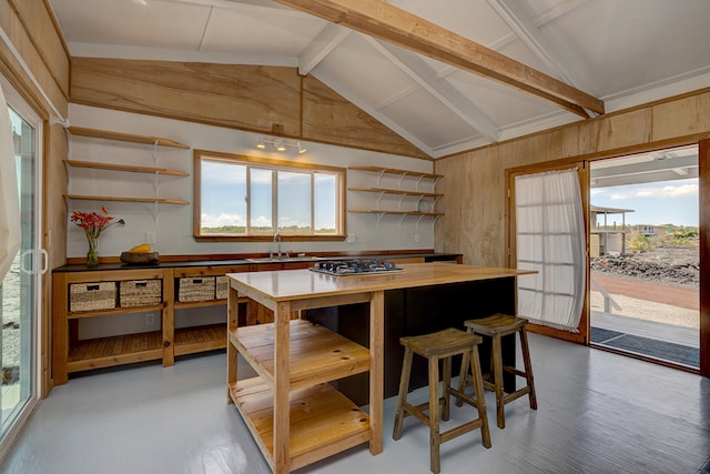 kitchen featuring sink, light hardwood / wood-style flooring, wood walls, and beam ceiling