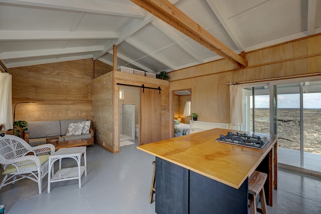 kitchen with a barn door, wood walls, and stainless steel gas stovetop