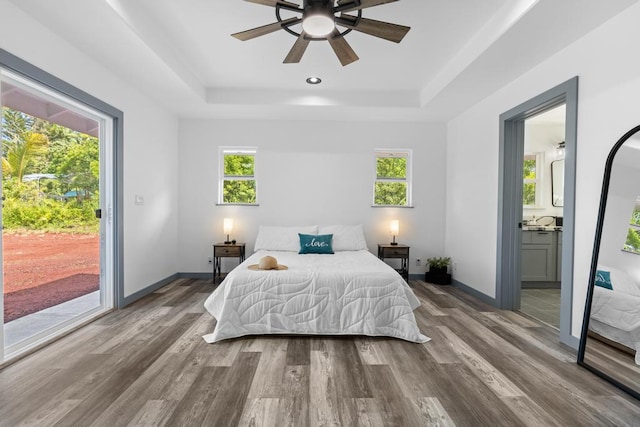 bedroom featuring multiple windows, connected bathroom, access to exterior, wood-type flooring, and ceiling fan