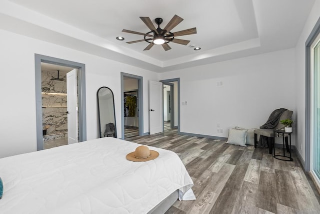 bedroom featuring wood-type flooring, connected bathroom, ceiling fan, and a raised ceiling