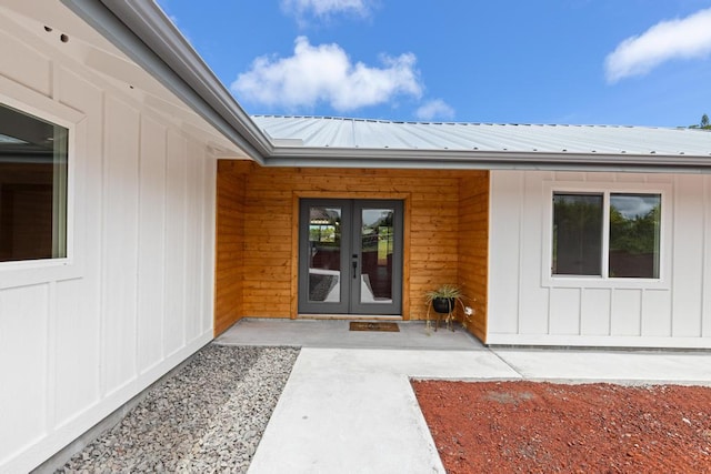 doorway to property with board and batten siding, french doors, and metal roof
