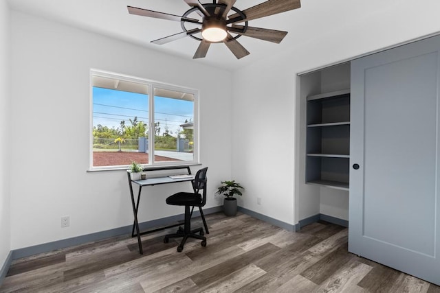 office area with ceiling fan, dark hardwood / wood-style flooring, and built in shelves