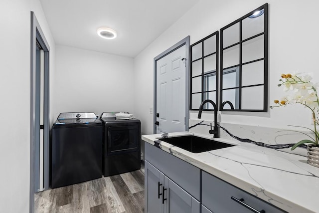 washroom with dark hardwood / wood-style floors, washer and clothes dryer, sink, and cabinets