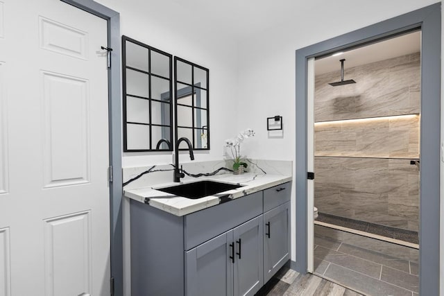 bathroom featuring vanity, hardwood / wood-style floors, toilet, and tiled shower