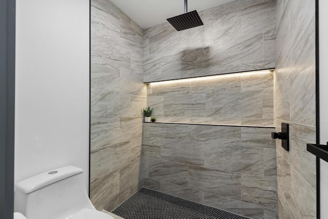 bathroom featuring a tile shower and toilet