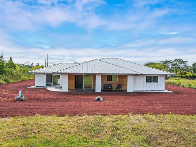 back of property featuring a lawn, board and batten siding, and metal roof
