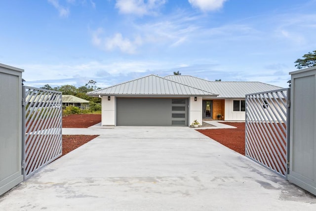 modern home with a garage, concrete driveway, and metal roof