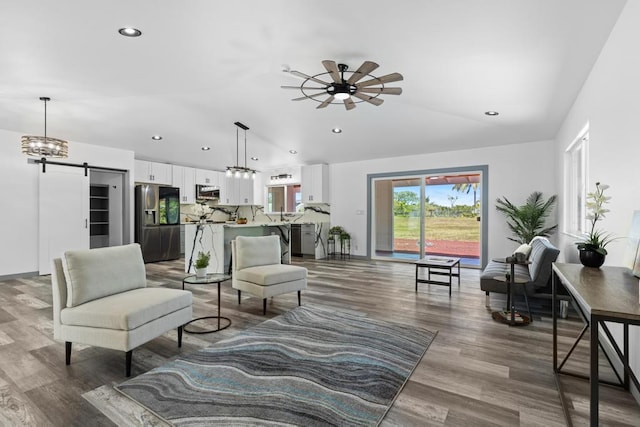 living room with a barn door, ceiling fan, and dark wood-type flooring