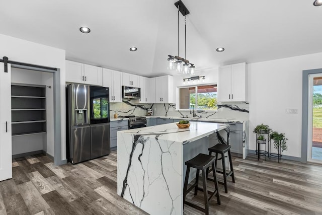 kitchen featuring hanging light fixtures, white cabinetry, dark wood-type flooring, a kitchen island, and stainless steel appliances