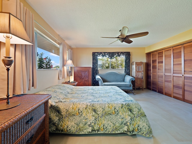 bedroom with ceiling fan, a textured ceiling, and multiple windows