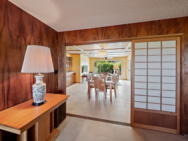 interior space featuring an inviting chandelier, wood walls, and a textured ceiling