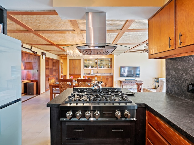 kitchen with stainless steel gas stovetop, kitchen peninsula, island exhaust hood, and refrigerator