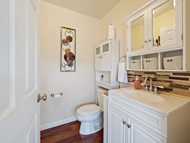 bathroom featuring wood-type flooring, vanity, toilet, and tasteful backsplash