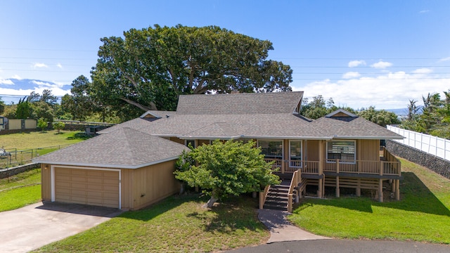 view of front facade featuring covered porch, a front yard, and a garage