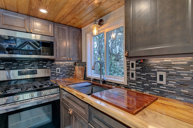 kitchen with appliances with stainless steel finishes, sink, tasteful backsplash, and wood counters