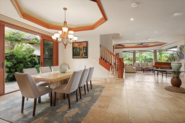 dining area featuring ceiling fan with notable chandelier, a raised ceiling, and crown molding