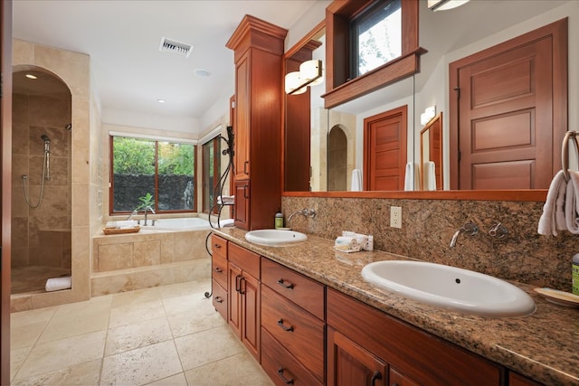 bathroom featuring vanity, plus walk in shower, tasteful backsplash, and a wealth of natural light