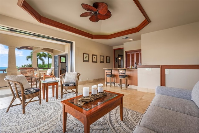 living room featuring light tile patterned floors, a tray ceiling, and ceiling fan