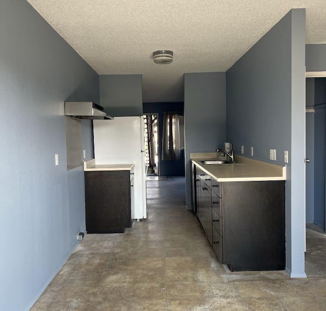 kitchen with dark brown cabinets, sink, a textured ceiling, and wall chimney exhaust hood