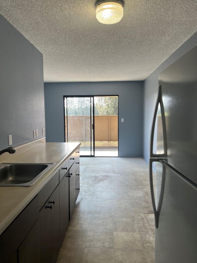 kitchen featuring sink, black refrigerator, and a textured ceiling