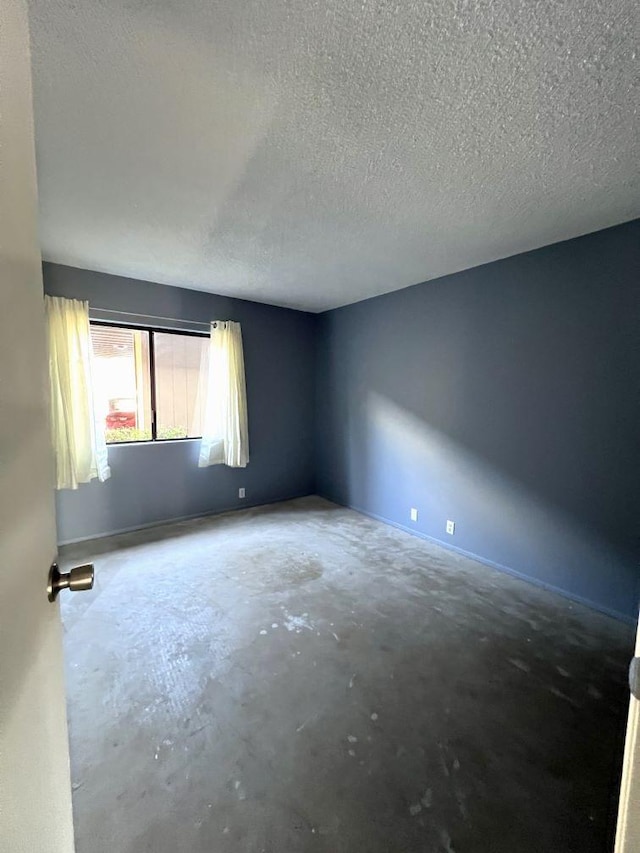 empty room with concrete floors and a textured ceiling