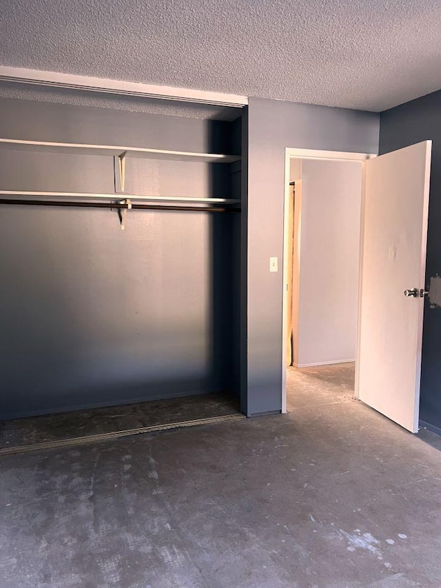 unfurnished bedroom featuring a textured ceiling, a closet, and concrete flooring