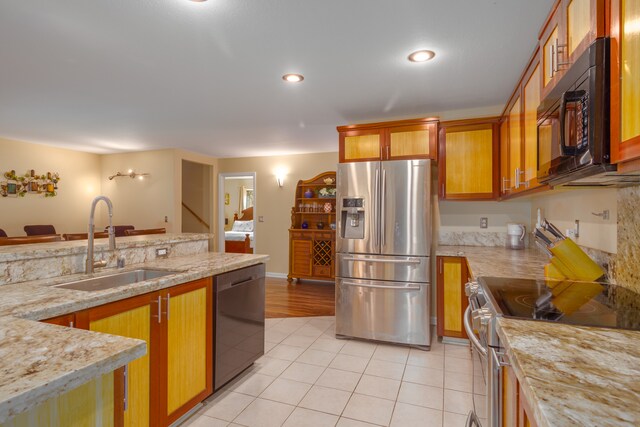kitchen featuring black appliances, light stone counters, and sink