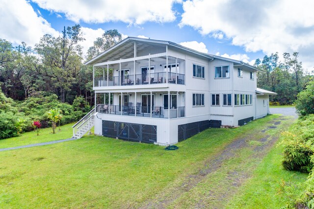rear view of property featuring a lawn, a balcony, and covered porch