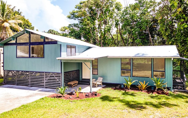 view of front facade featuring a patio, a front yard, entry steps, and metal roof