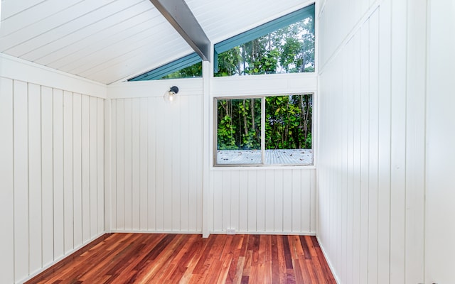 spare room with wooden walls, lofted ceiling with beams, and dark hardwood / wood-style flooring