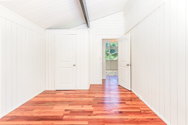 interior space with lofted ceiling with beams, wood walls, and light hardwood / wood-style flooring