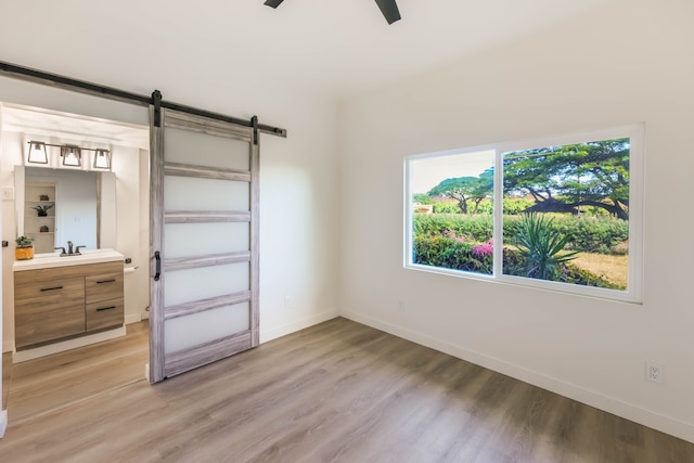 bedroom with ceiling fan, light hardwood / wood-style flooring, and a barn door