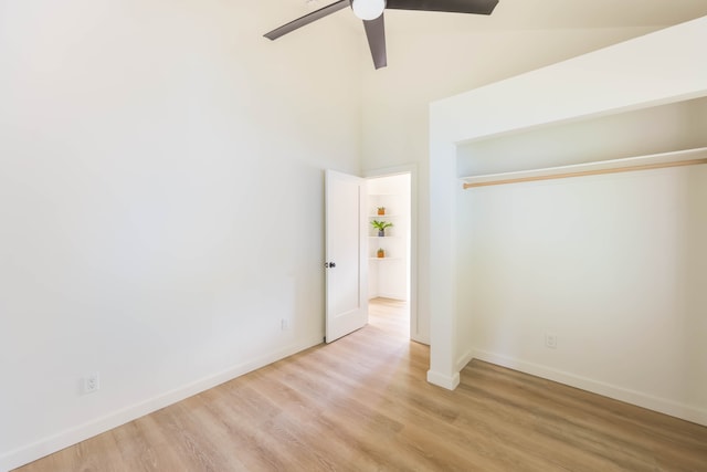 unfurnished bedroom featuring light wood-type flooring, a high ceiling, and ceiling fan