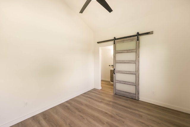 interior space featuring ceiling fan, hardwood / wood-style flooring, a barn door, and high vaulted ceiling