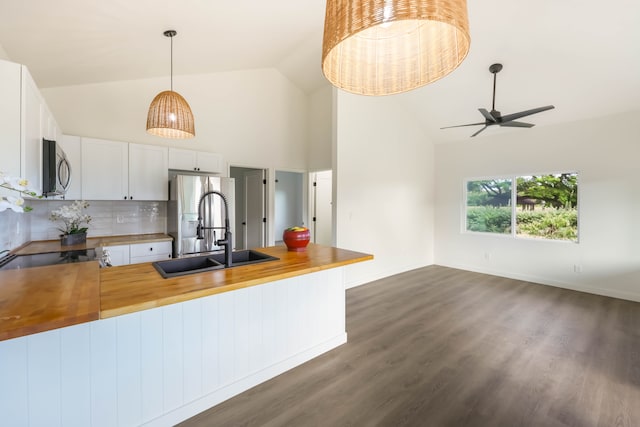 kitchen with white cabinets, sink, kitchen peninsula, wooden counters, and dark wood-type flooring