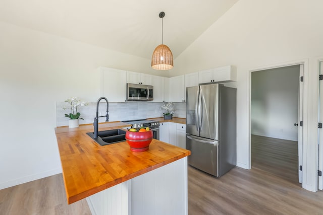 kitchen with white cabinets, kitchen peninsula, sink, wooden counters, and appliances with stainless steel finishes