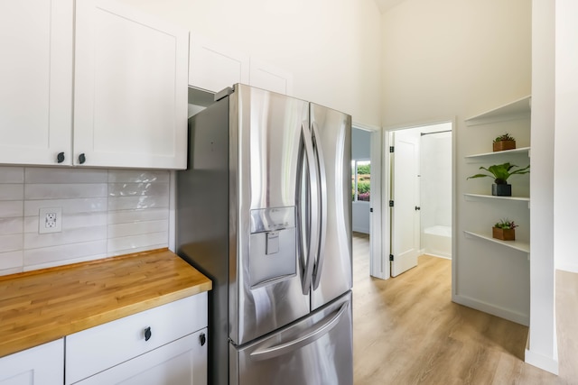 kitchen with white cabinets, tasteful backsplash, butcher block countertops, stainless steel refrigerator with ice dispenser, and light wood-type flooring