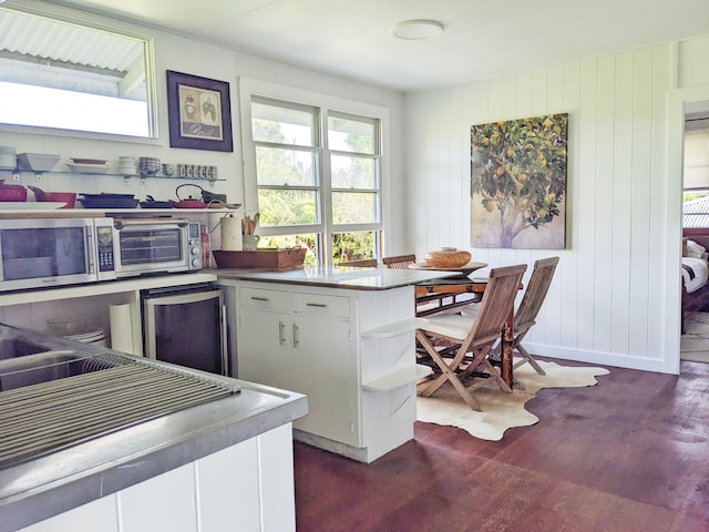 kitchen with white cabinets, open shelves, dark wood-style floors, stainless steel microwave, and fridge
