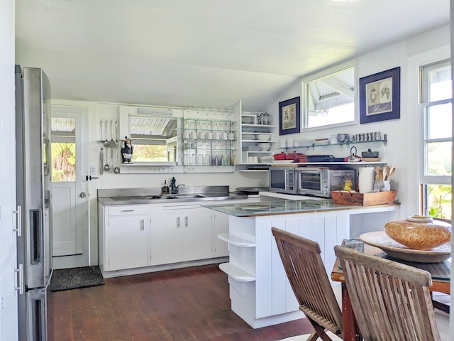 kitchen featuring open shelves, stainless steel fridge, stainless steel countertops, white cabinetry, and lofted ceiling